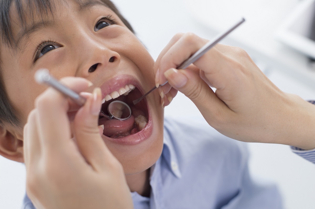 Criança abre a boca para o dentista. A escolha do dentista é muito importante desde a infância,